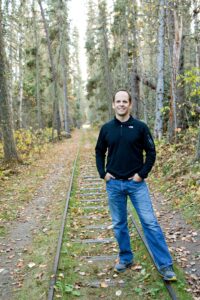 Kregg a physiotherapist standing in a forest smiling